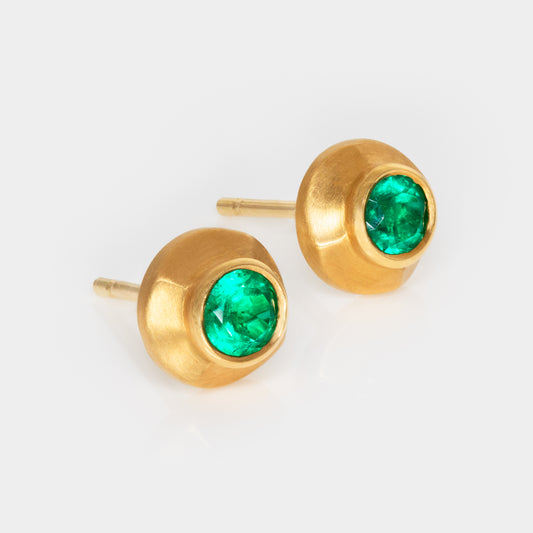 Gold earrings with green gemstones on a white background