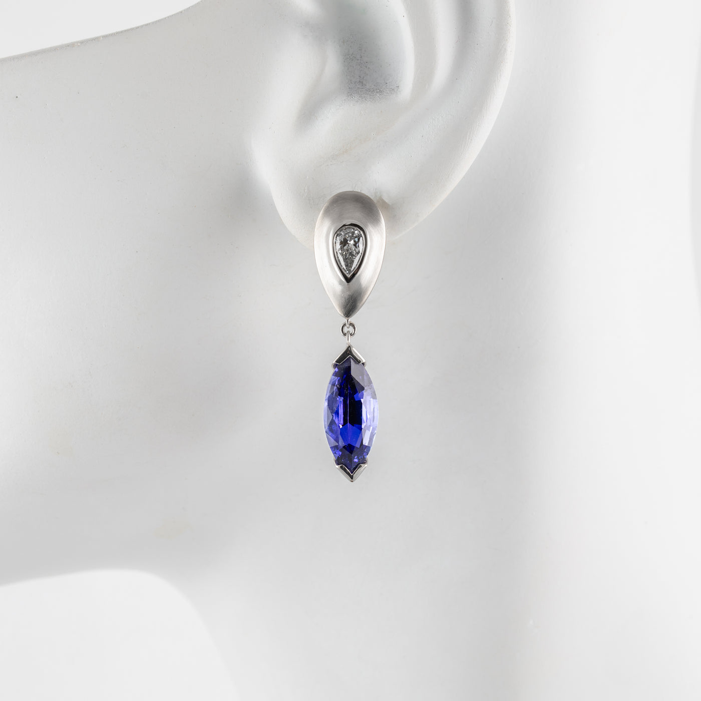 Platinum earring with a tanzanite gemstone on a mannequin ear.