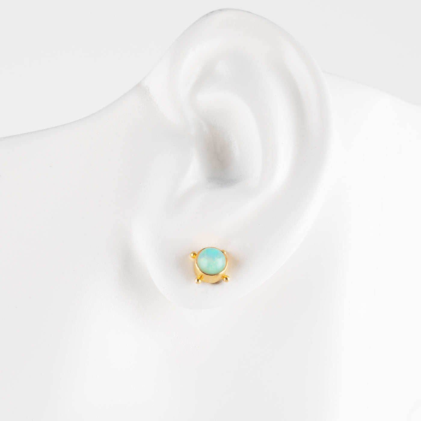 Gold earring with opal on a white mannequin