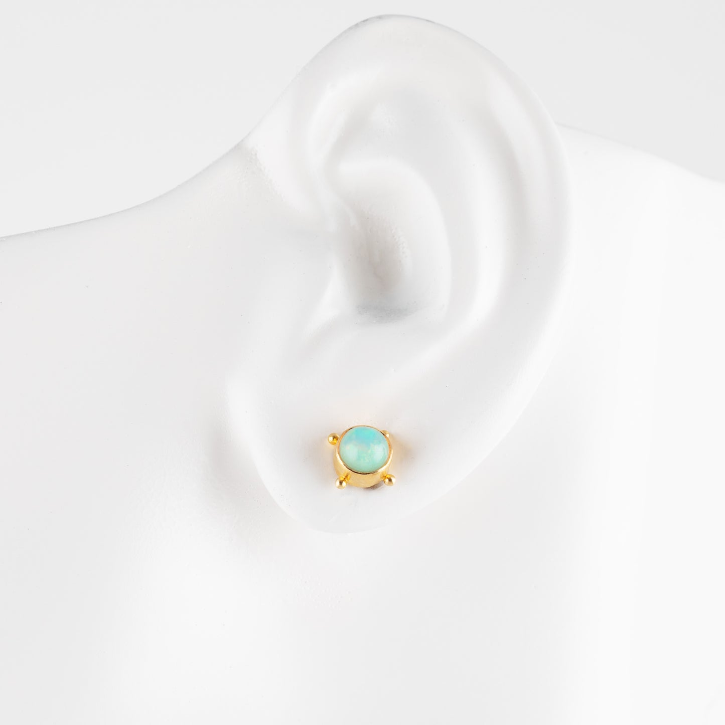 Gold earring with opal on a white mannequin