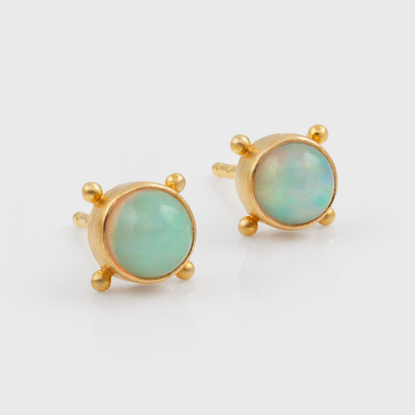 Gold earrings with opals on a white background