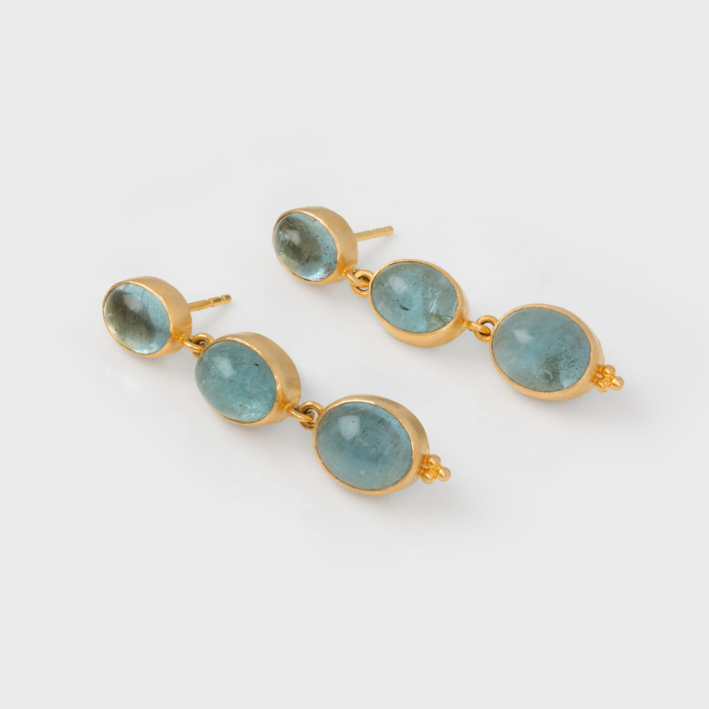 Pair of earrings with gold frames and aquamarine gemstones on a white background