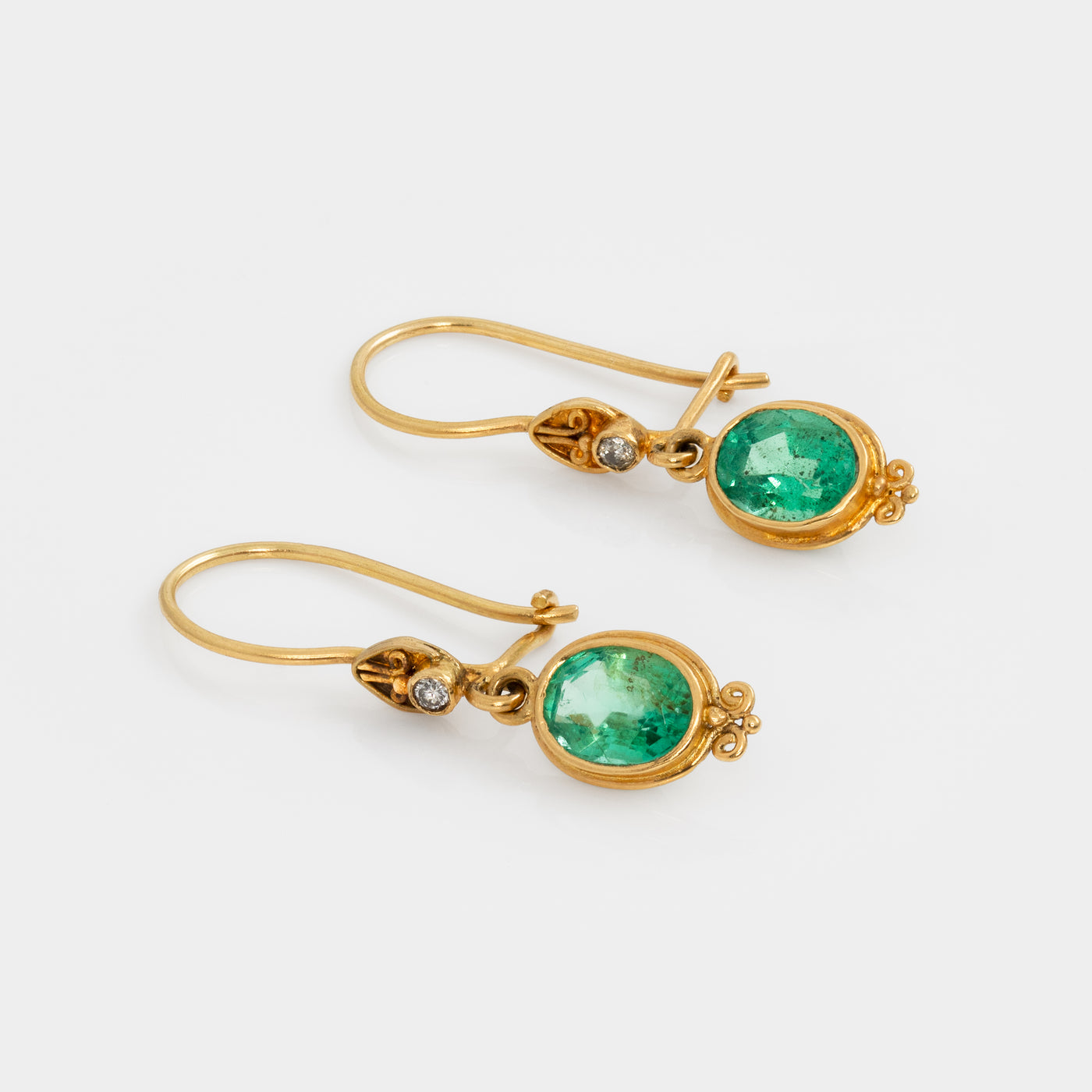 Gold earrings with green gemstones on a white background