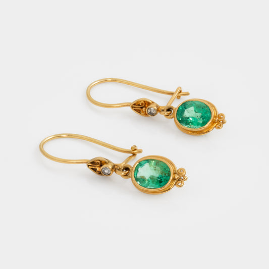 Gold earrings with green gemstones on a white background