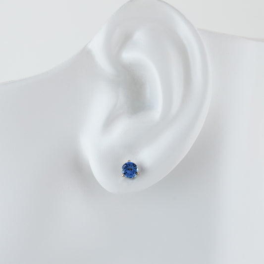 Single white gold stud earring featuring round blue Sapphire on white ear model