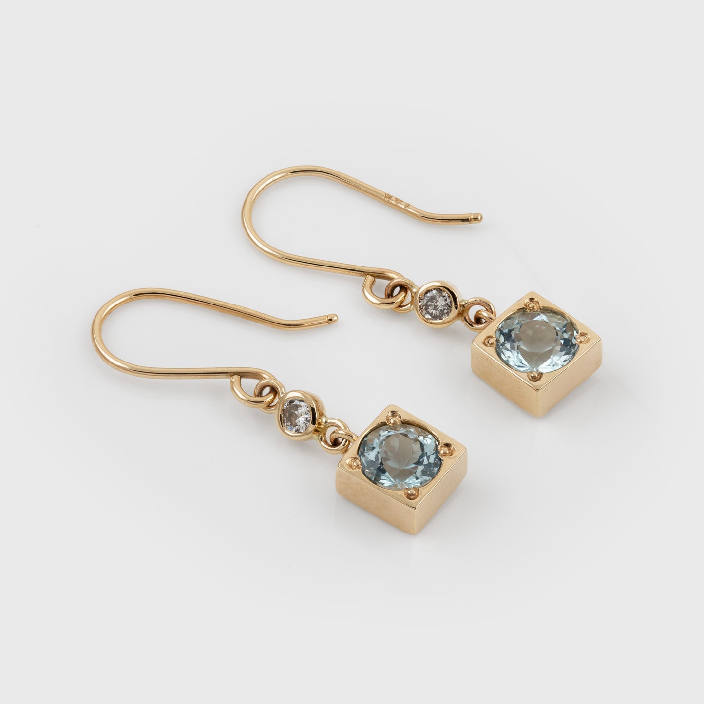 Gold earrings with blue aquamarine gemstones and diamond accents. 