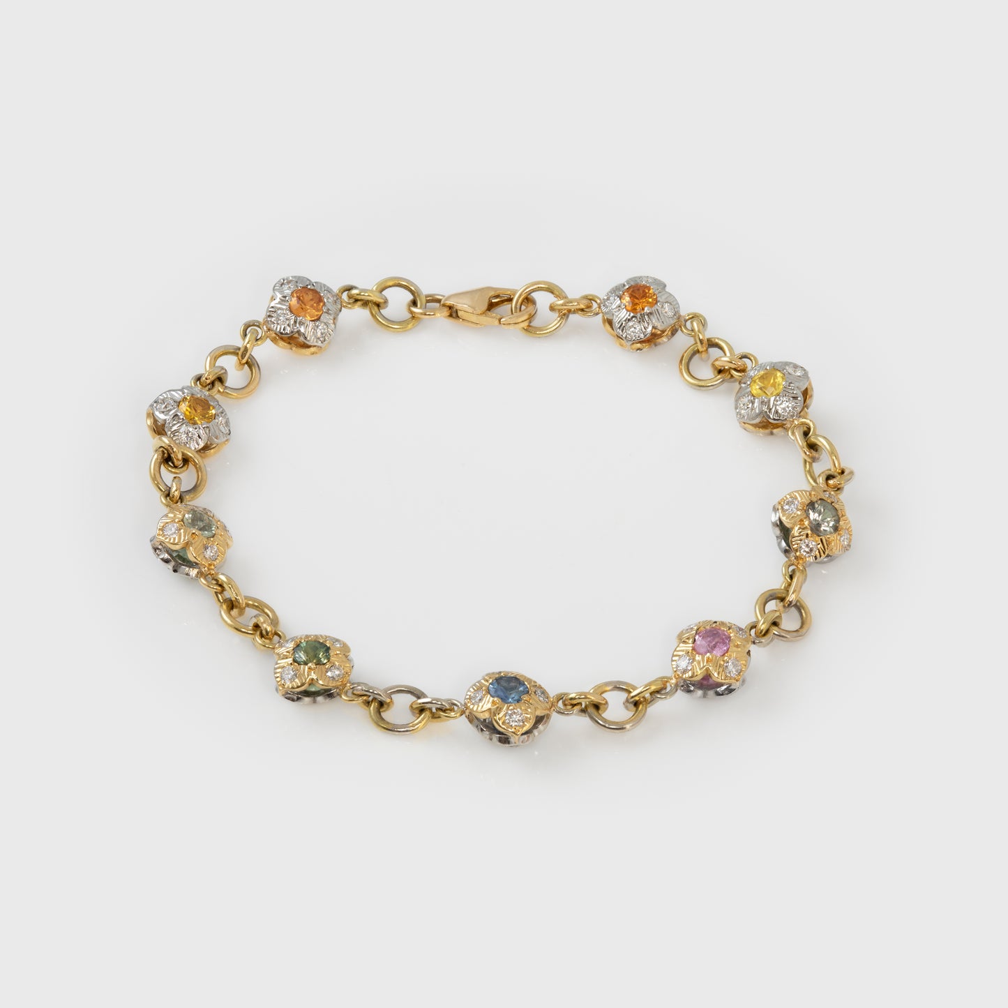 Gold bracelet with colorful gemstones on a white background
