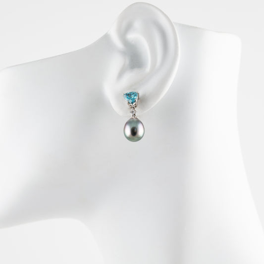 Pearl earring with a blue gemstone on a mannequin ear against a white background