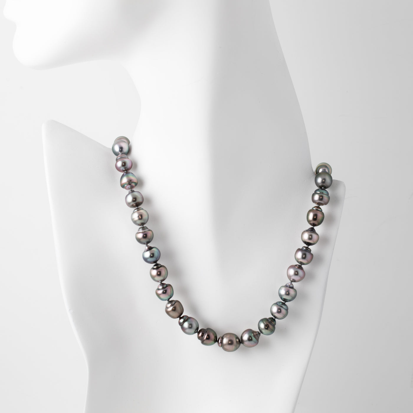 Strand of blue/purplish Tahitian pearls with a gold clasp on a white mannequin
