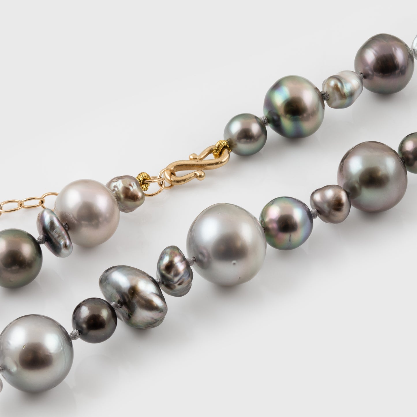 Pearl necklace with a gold clasp on a light gray background