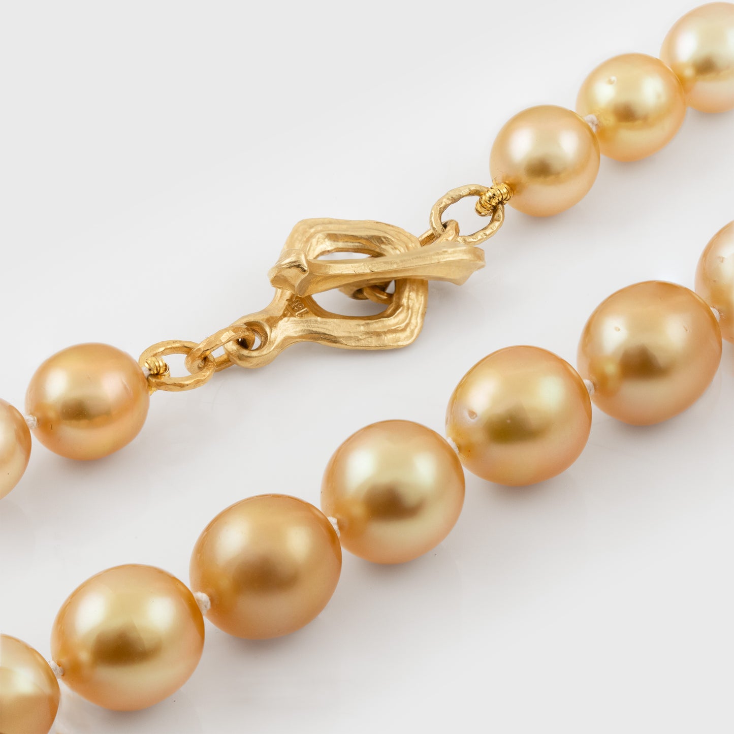 Gold pearl necklace with a gold clasp on a white background