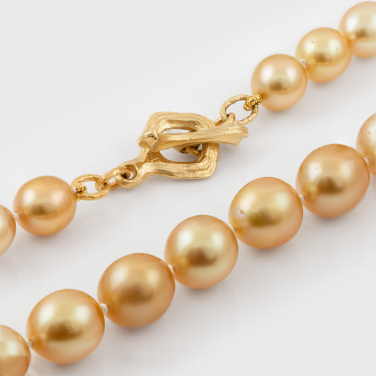 Gold pearl necklace with a gold clasp on a white background