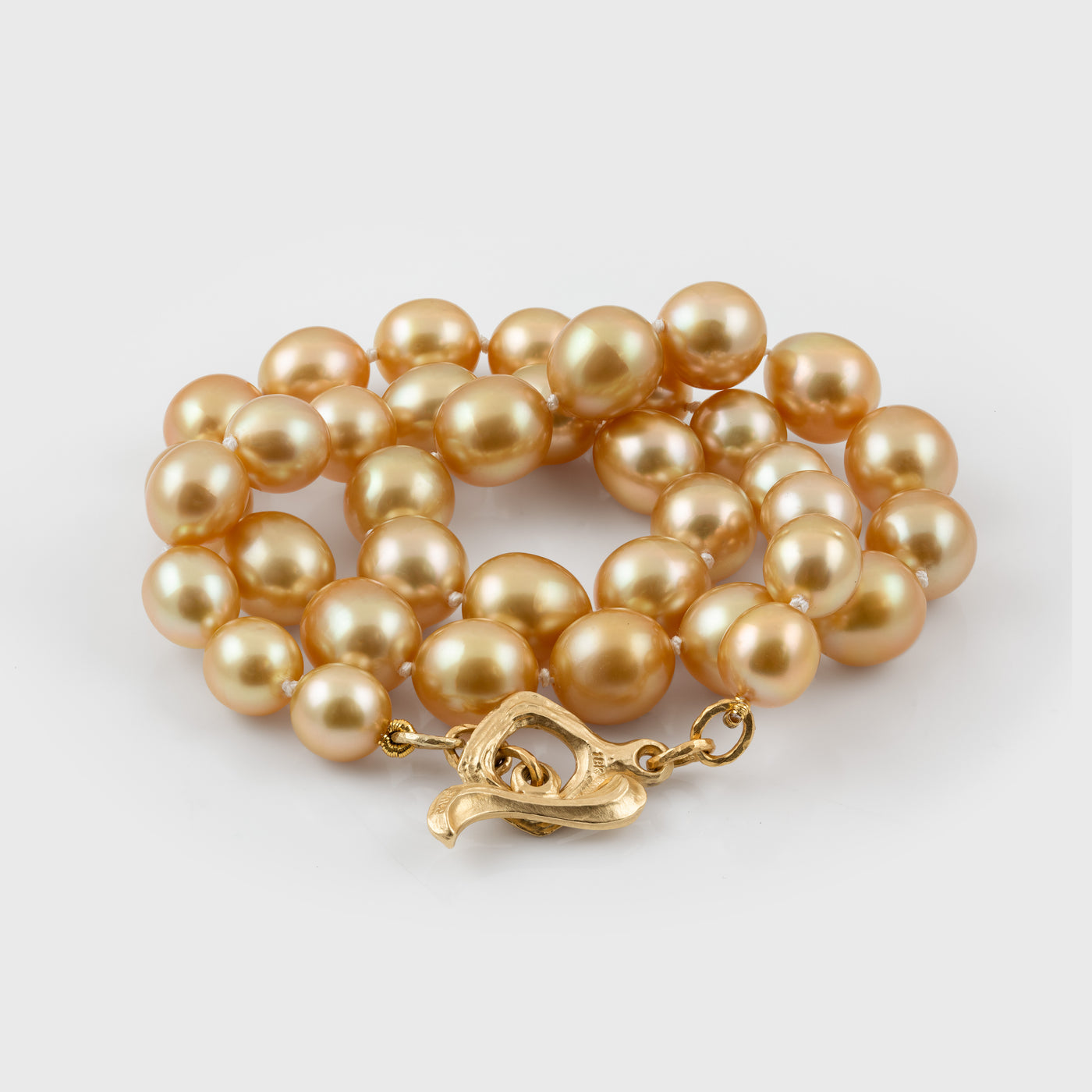 Gold pearl necklace with a gold clasp on a light gray background