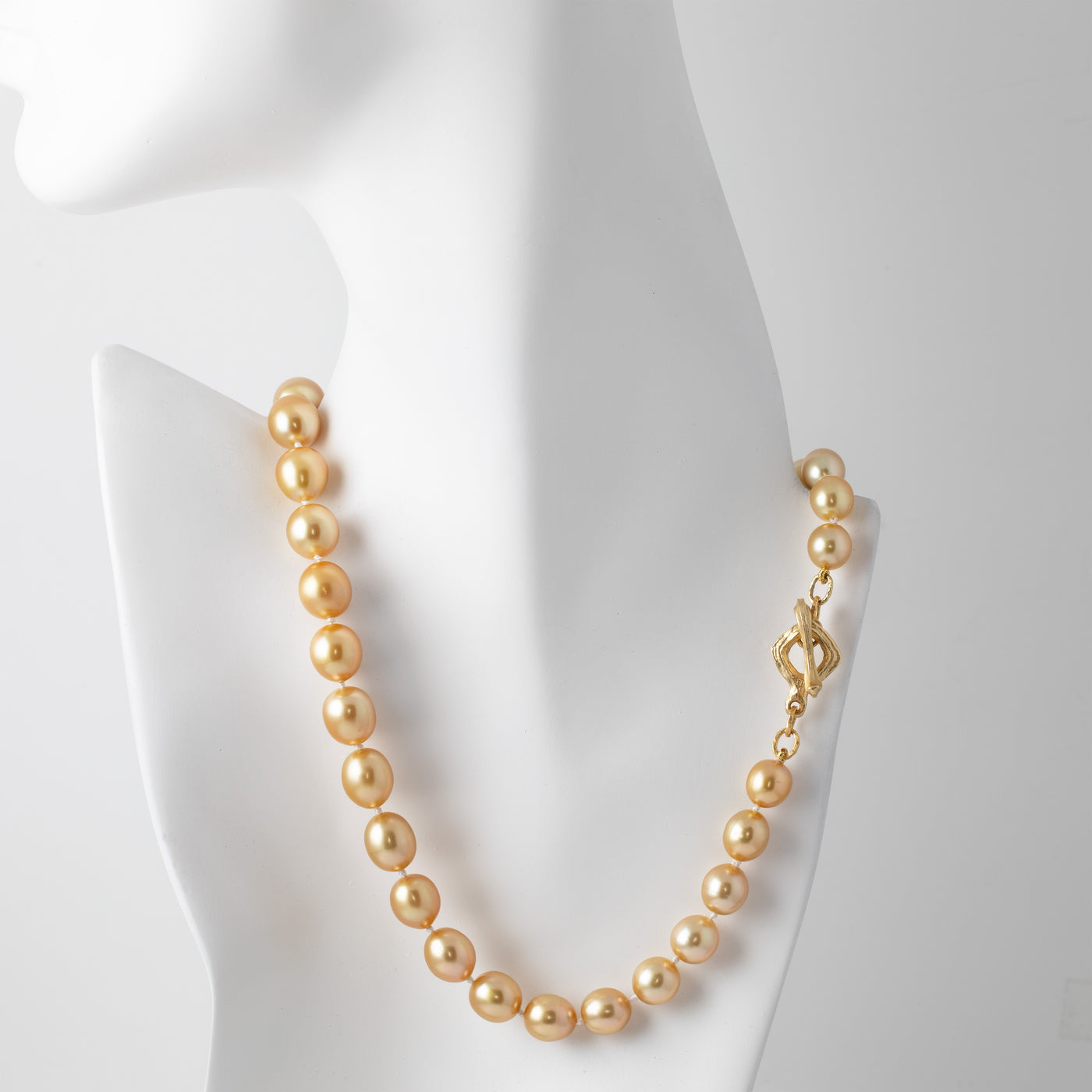 Gold pearl necklace on a mannequin with a white background