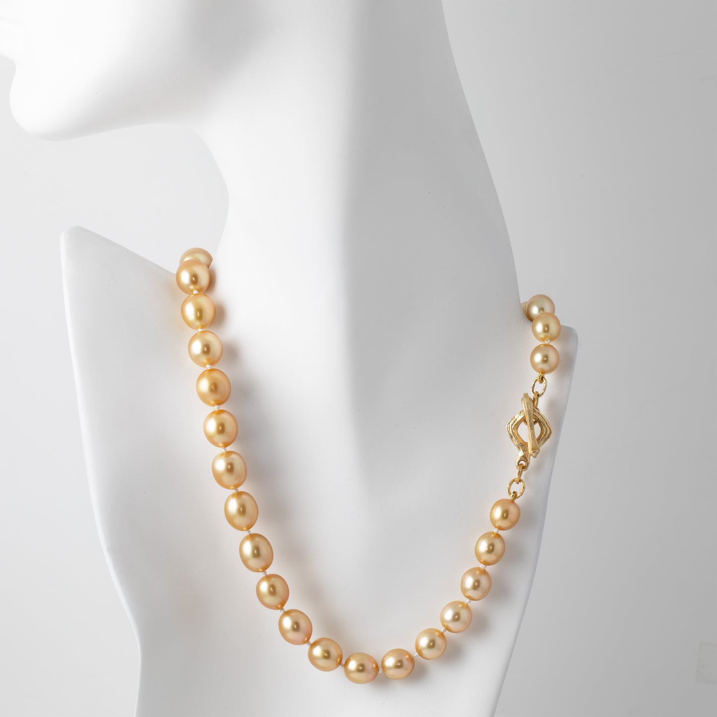 Gold pearl necklace on a mannequin with a white background