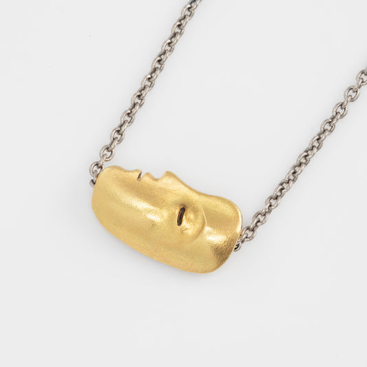Close-up of 18 karat yellow gold face pendant, suspended on a platinum cable chain with a lobster clasp.