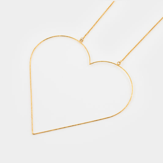 Gold heart-shaped necklace on a light gray background