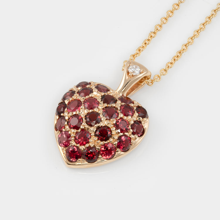 Heart-shaped pendant with red spinel gems on white background
