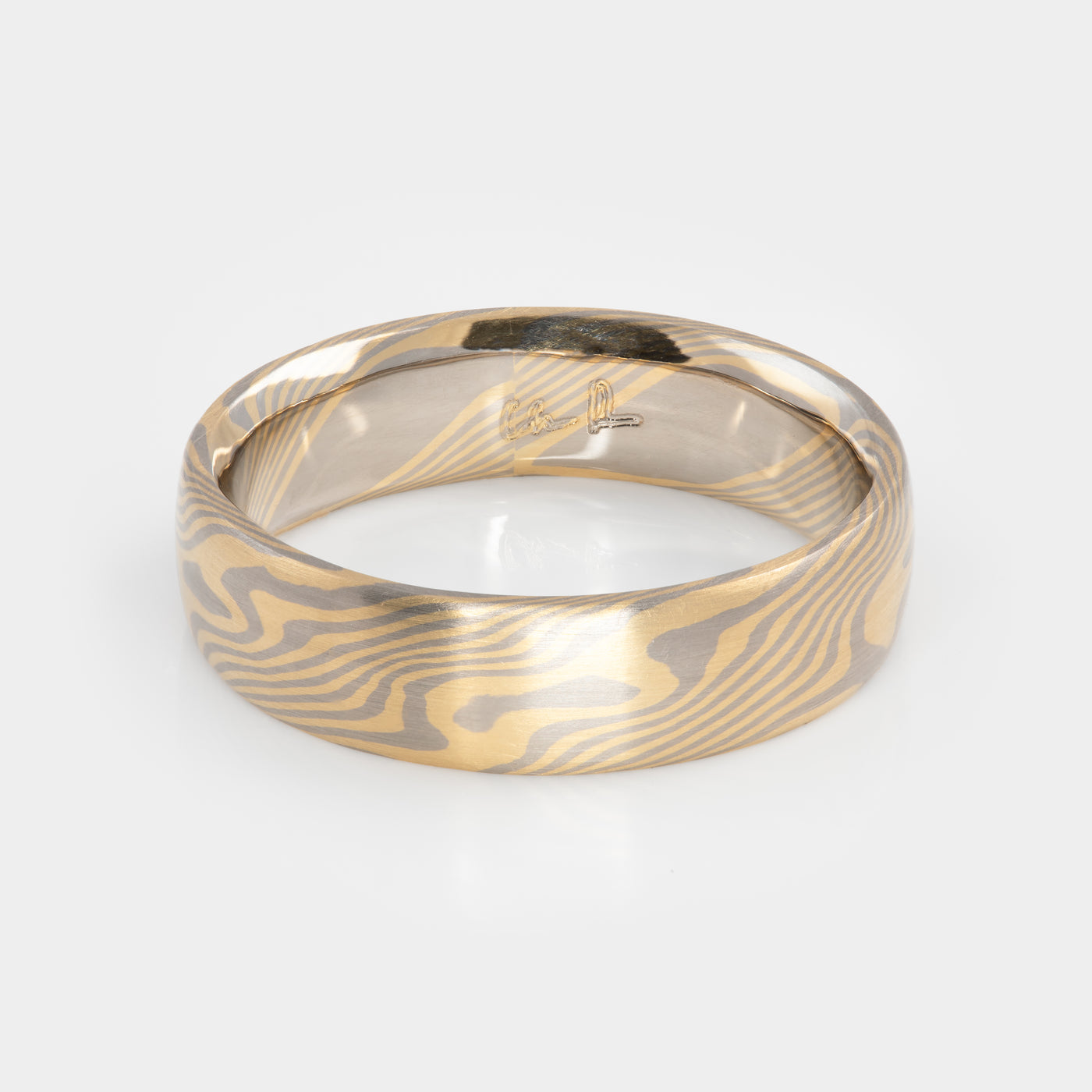 Gold and palladium ring with a mokume-gane design on a white background