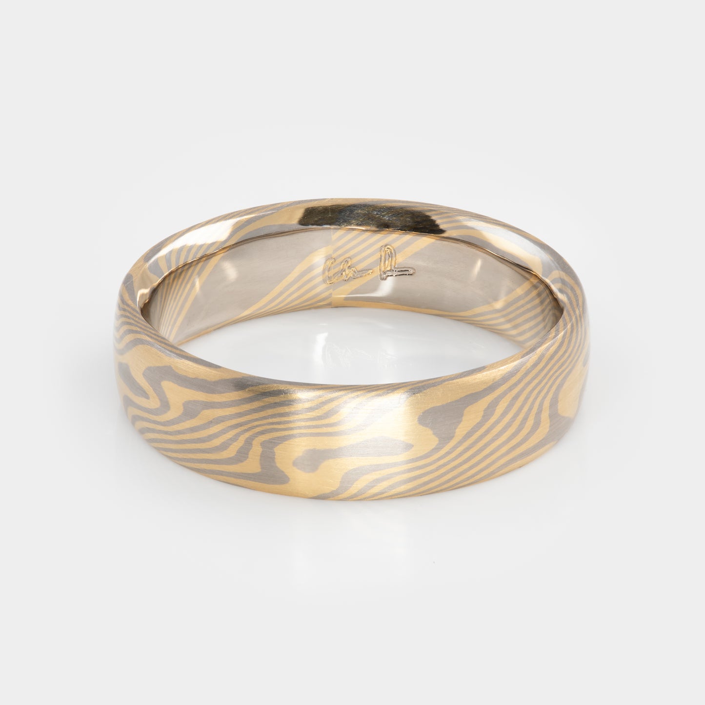 Gold and palladium ring with a mokume-gane design on a white background