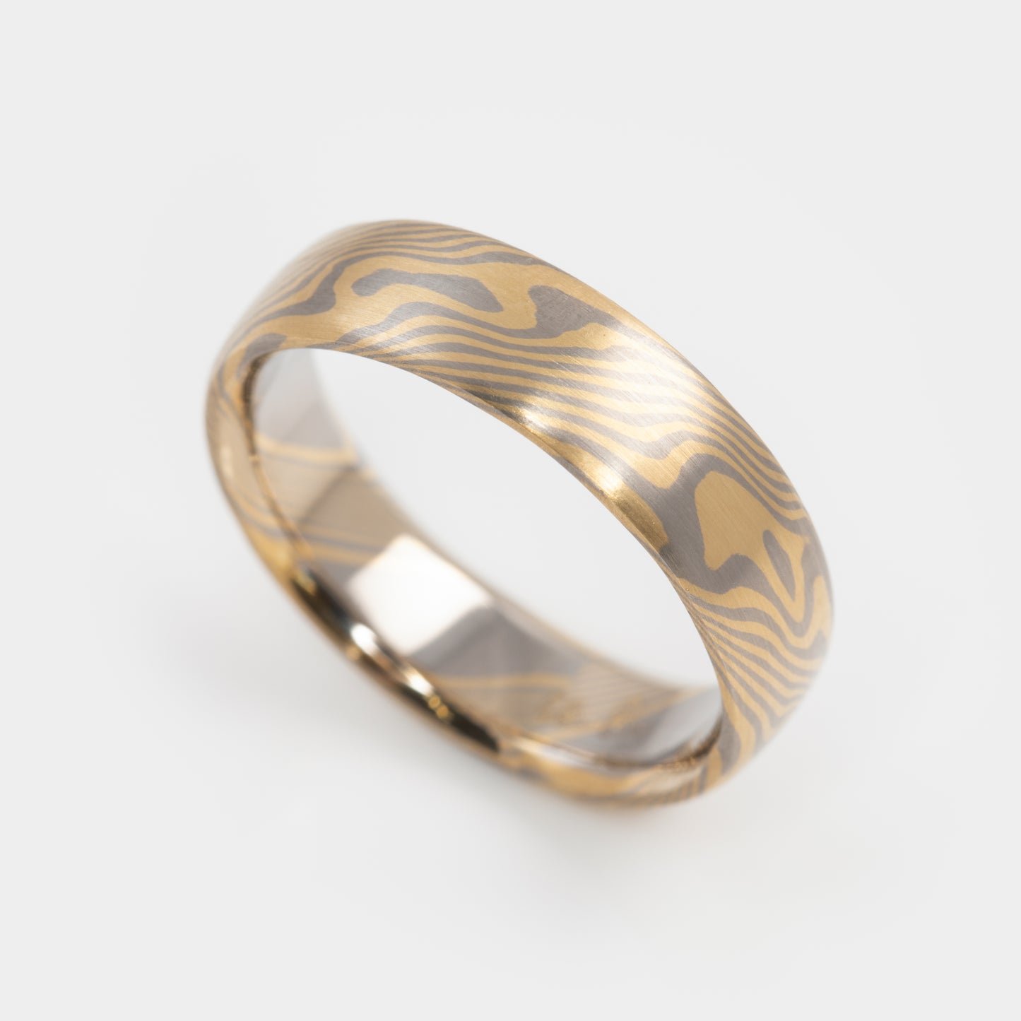 Gold and palladium ring with a mokume-gane design on a white background