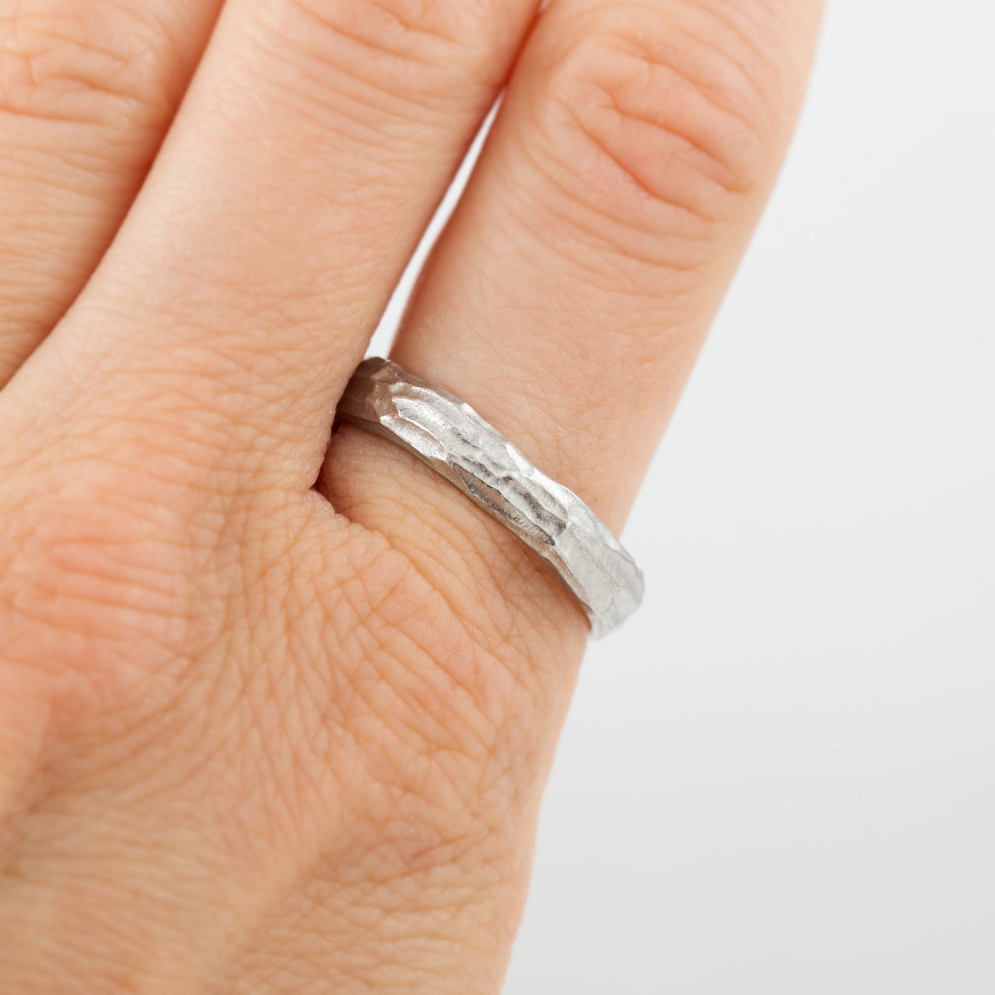 Plain platinum band with redwood bark texture on a hand