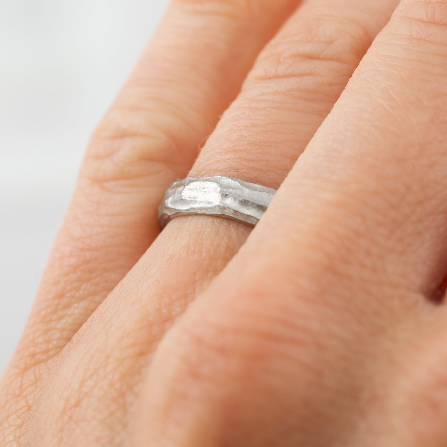 Plain platinum band with redwood bark texture on a hand