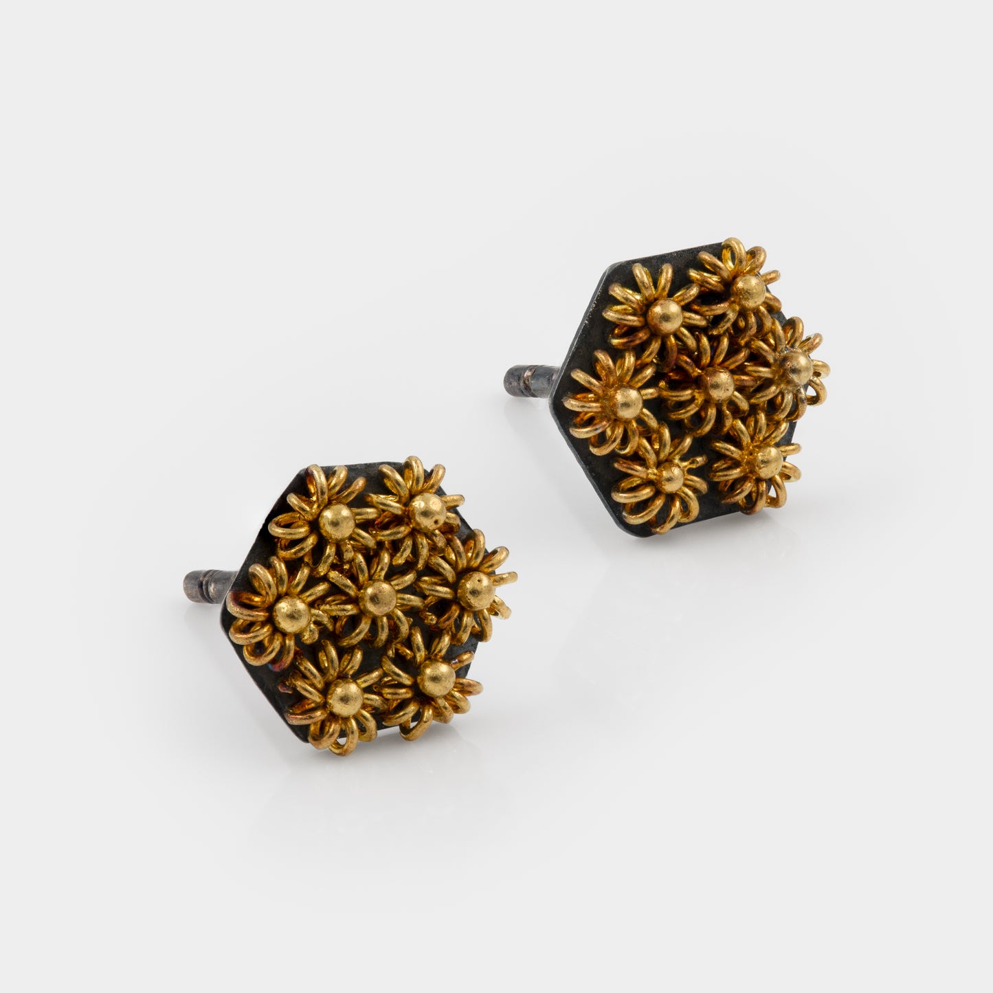 Pair of gold and black stud earrings on a white background