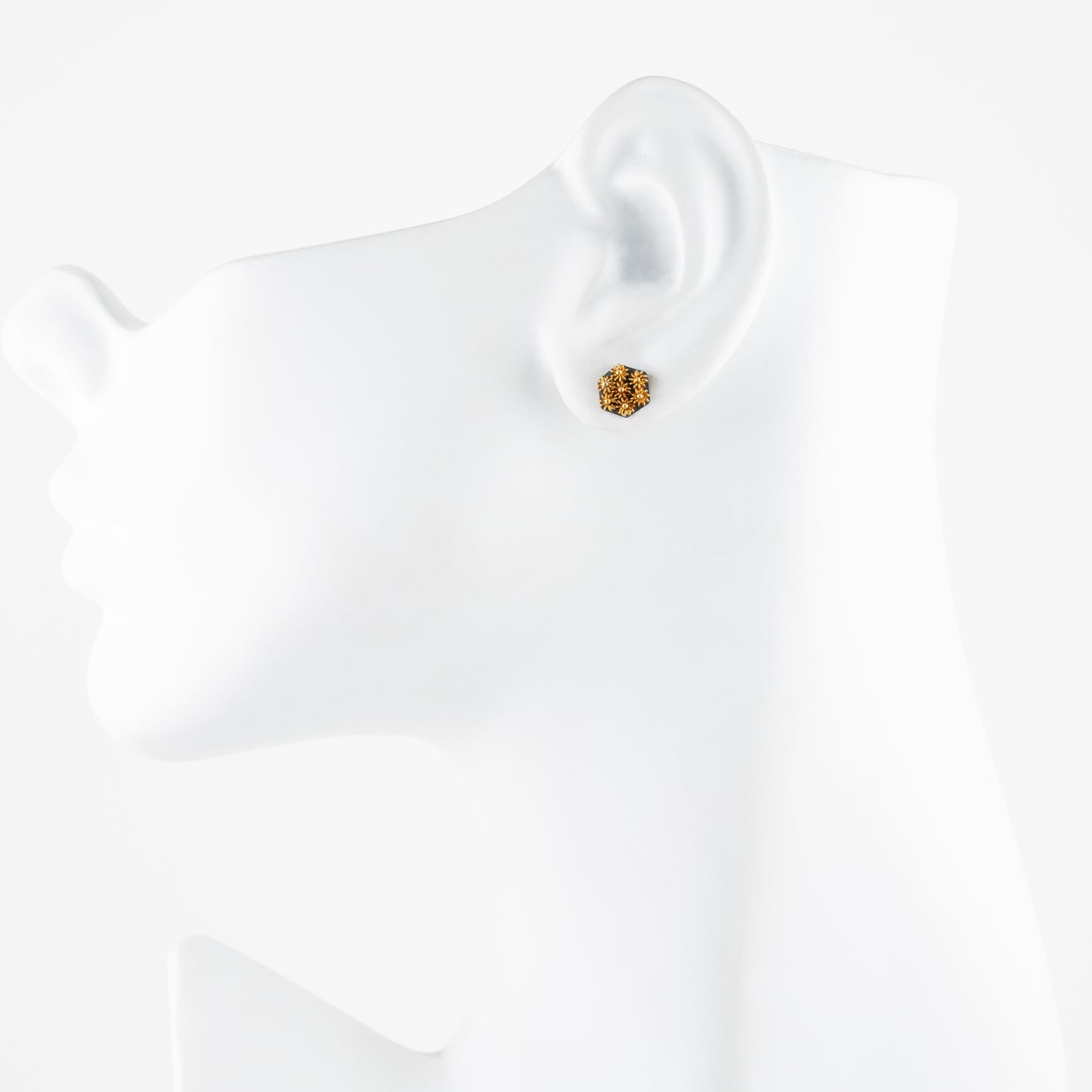 Gold earring on a white mannequin