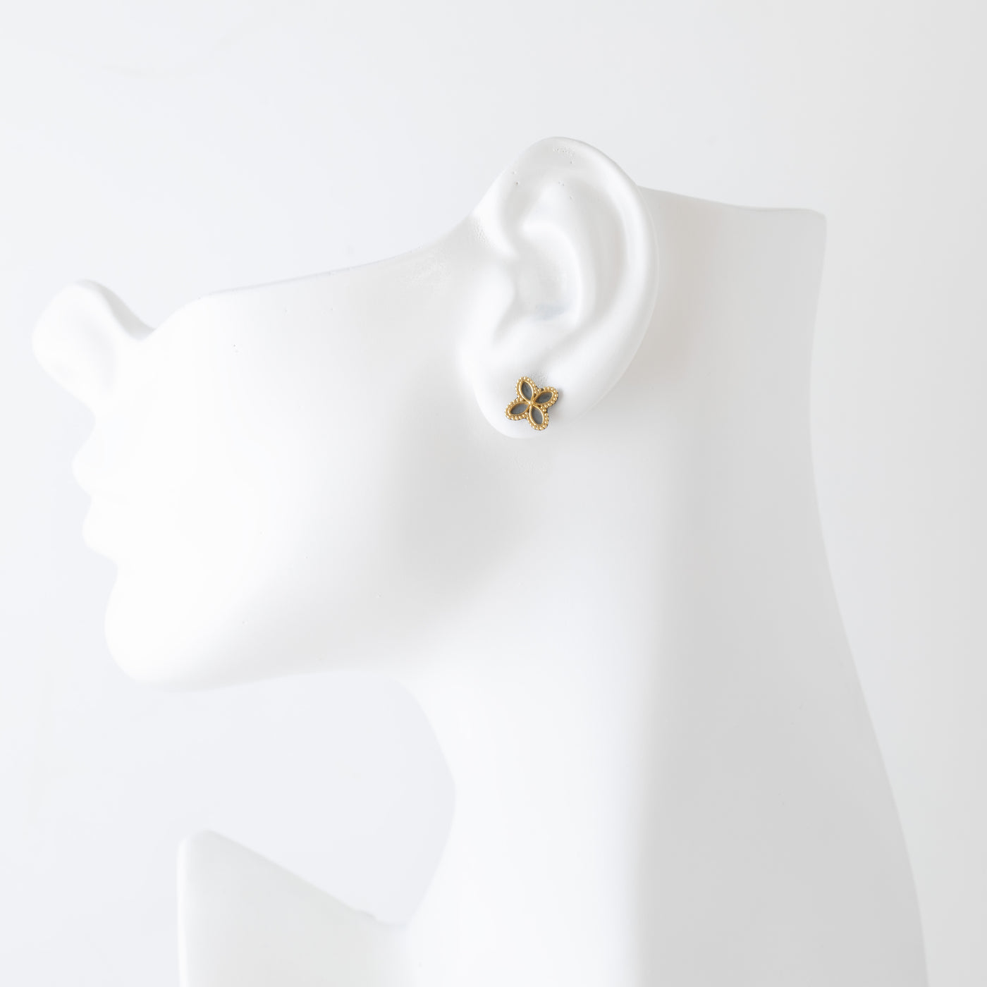 Clover-shaped earrings with gold and black design on a white mannequin