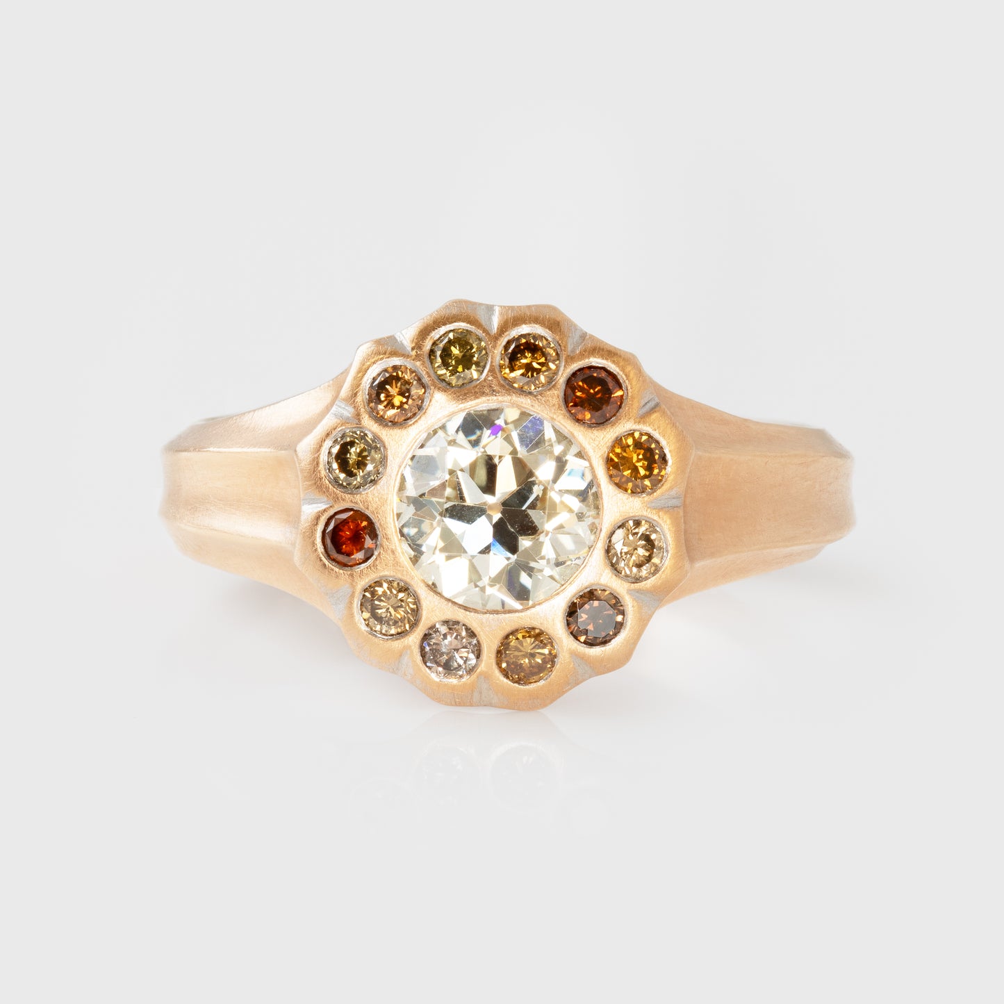 Rose gold ring with a central diamond and colored diamonds on a light gray background