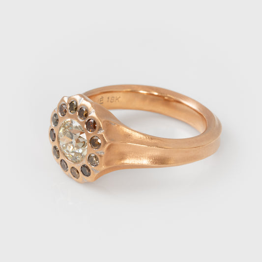 Rose gold ring with a central diamond and colored diamonds on a light gray background