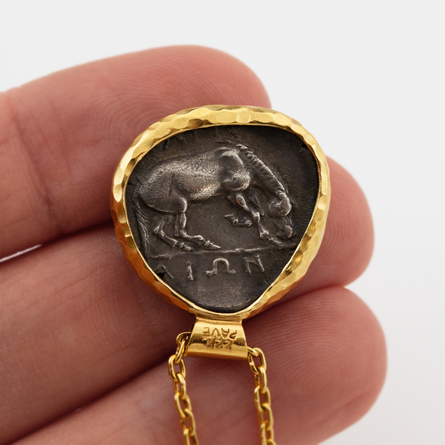 Gold necklace with an ancient coin pendant depicting a horse on a hand