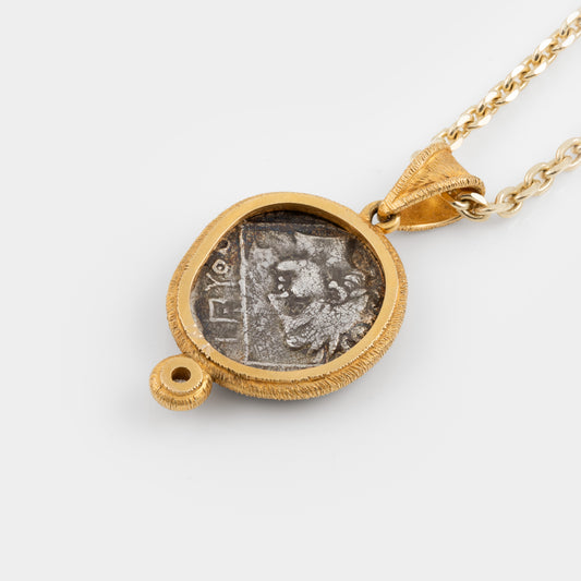 Gold pendant with a coin insert on a white background