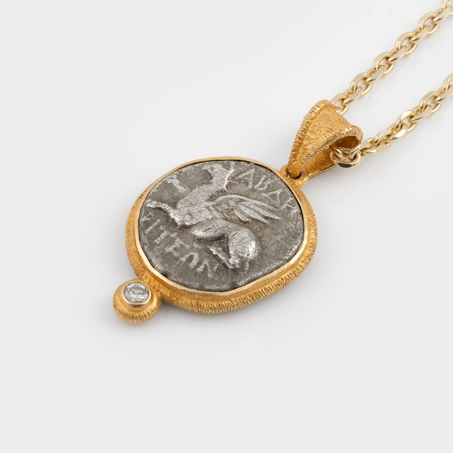 Gold pendant with an ancient coin featuring a winged horse on a white background