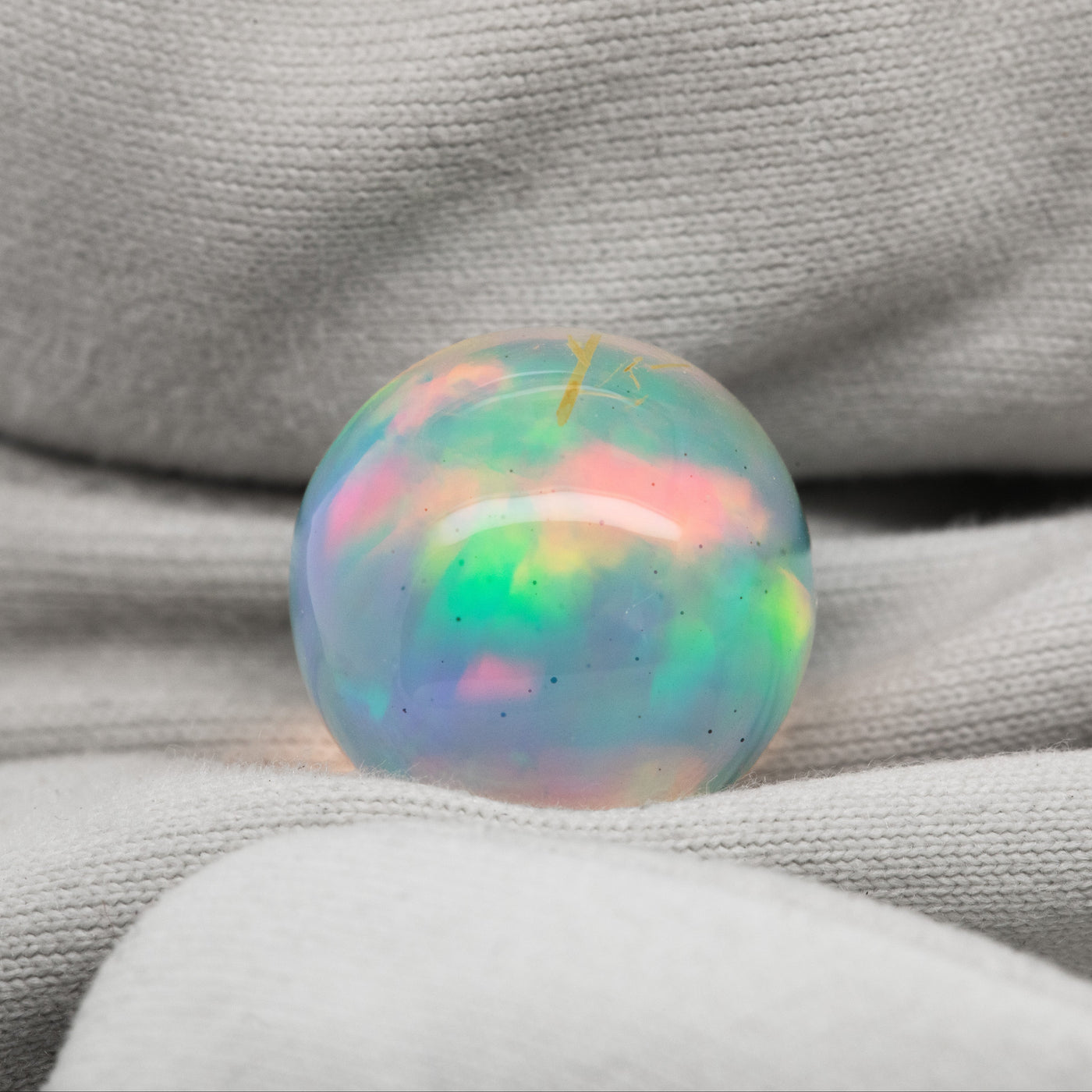Multicolor opal sphere on a white fabric background
