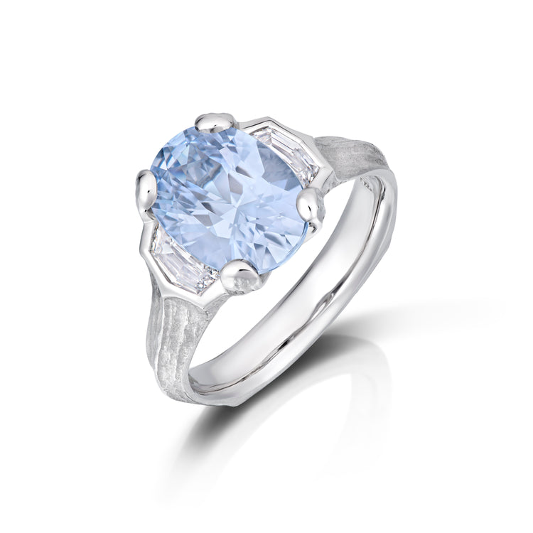 Top view of platinum ring with a large blue gemstone on a white background