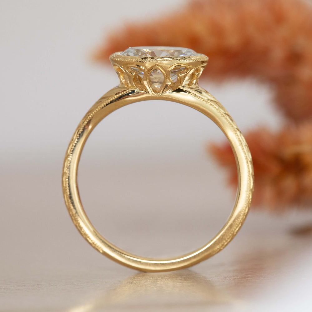 Side view of yellow gold ring with hand engraving and center diamond