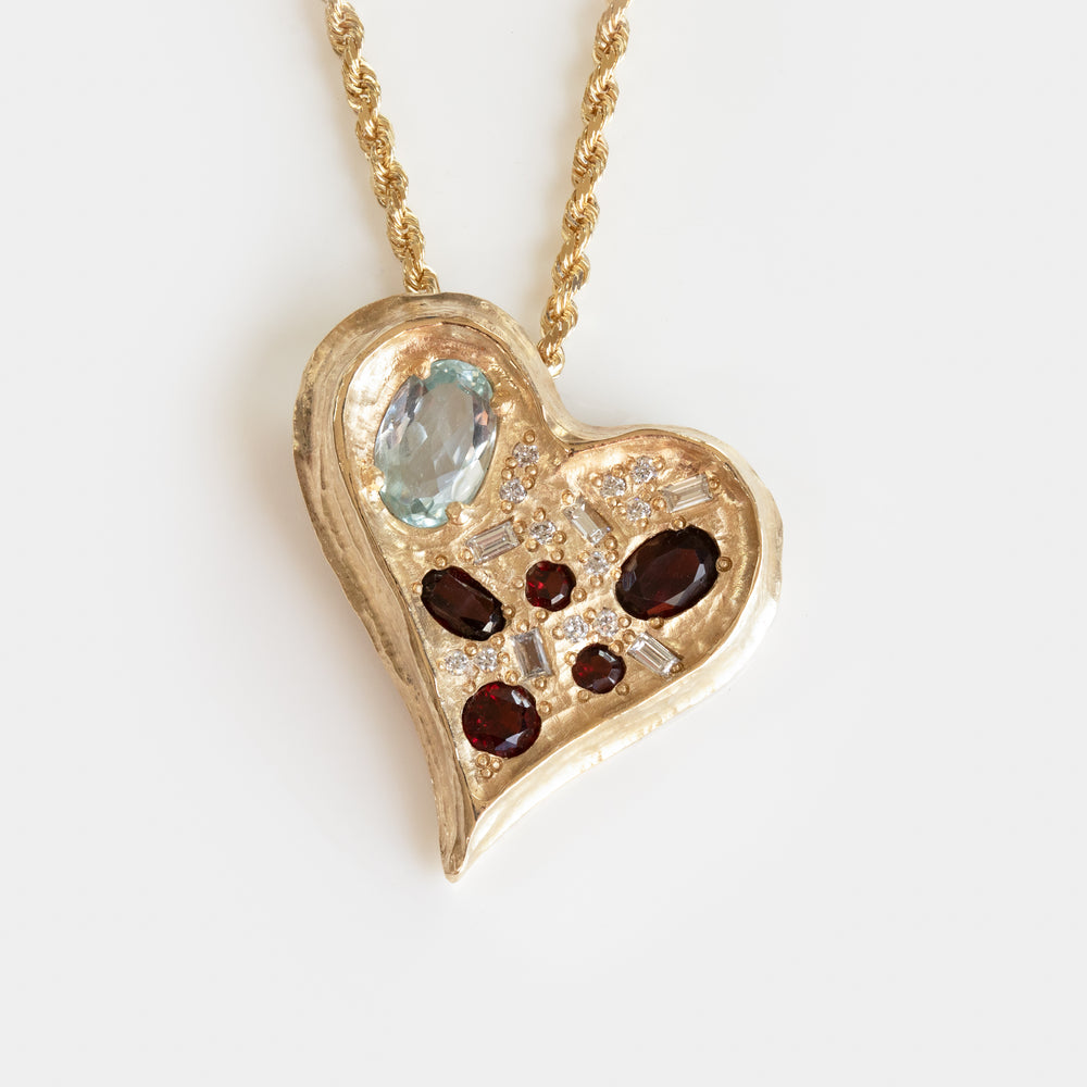 Gold heart-shaped pendant with a variety of gemstones on a white background