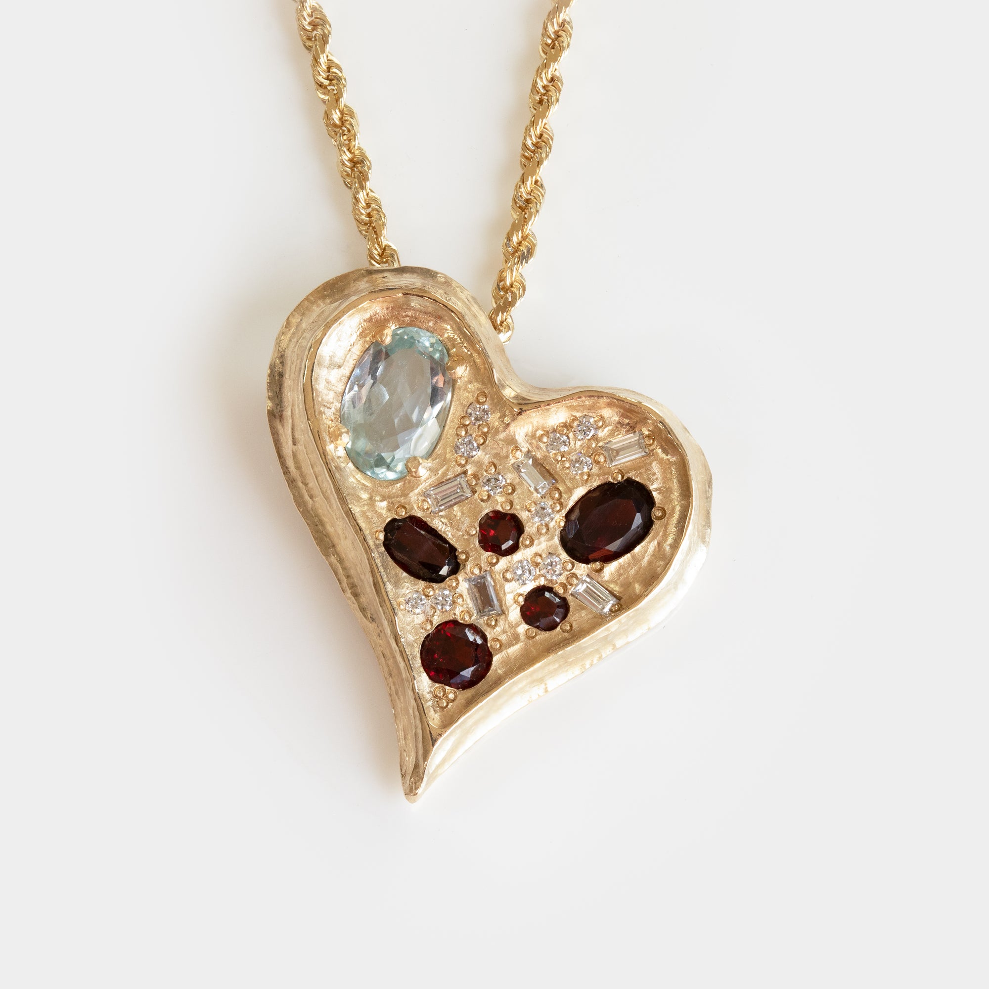 Gold heart-shaped pendant with a variety of gemstones on a white background