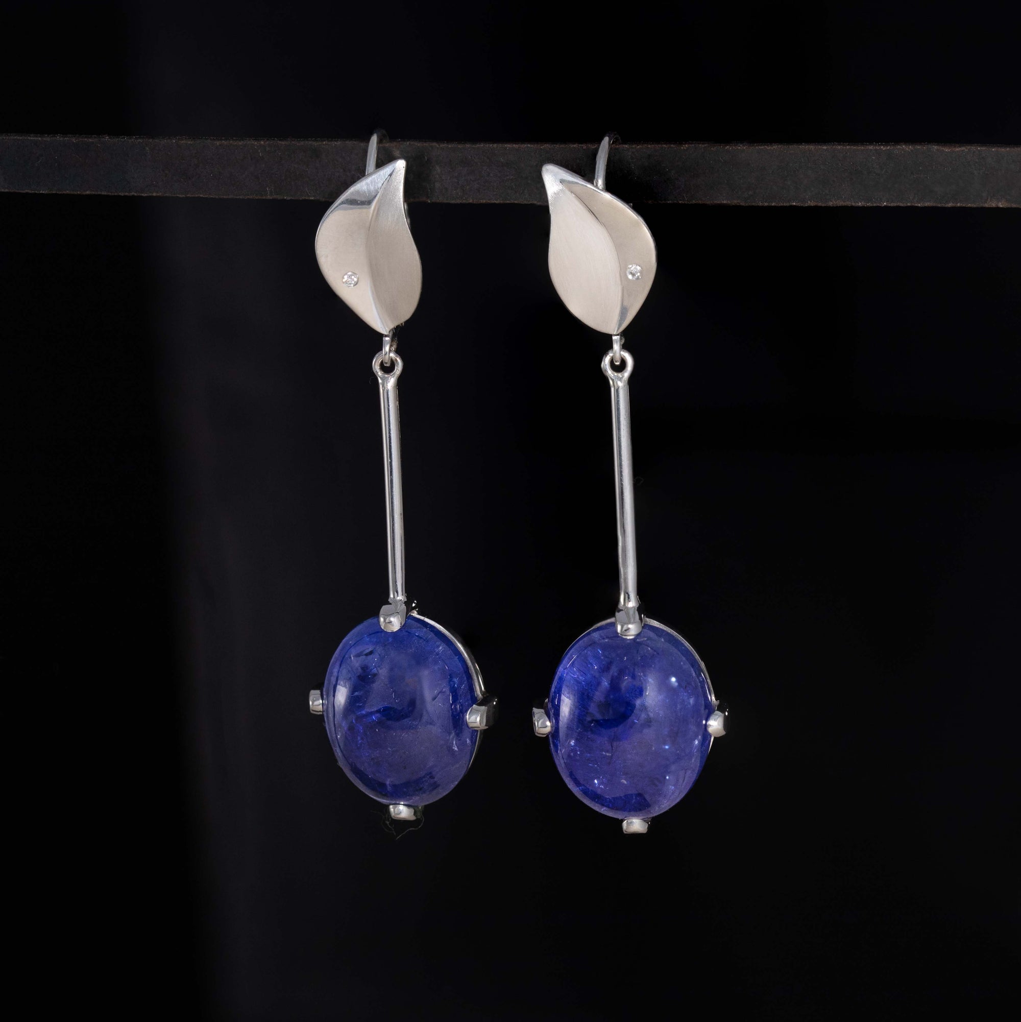 Silver earrings with blue gemstones on a black background