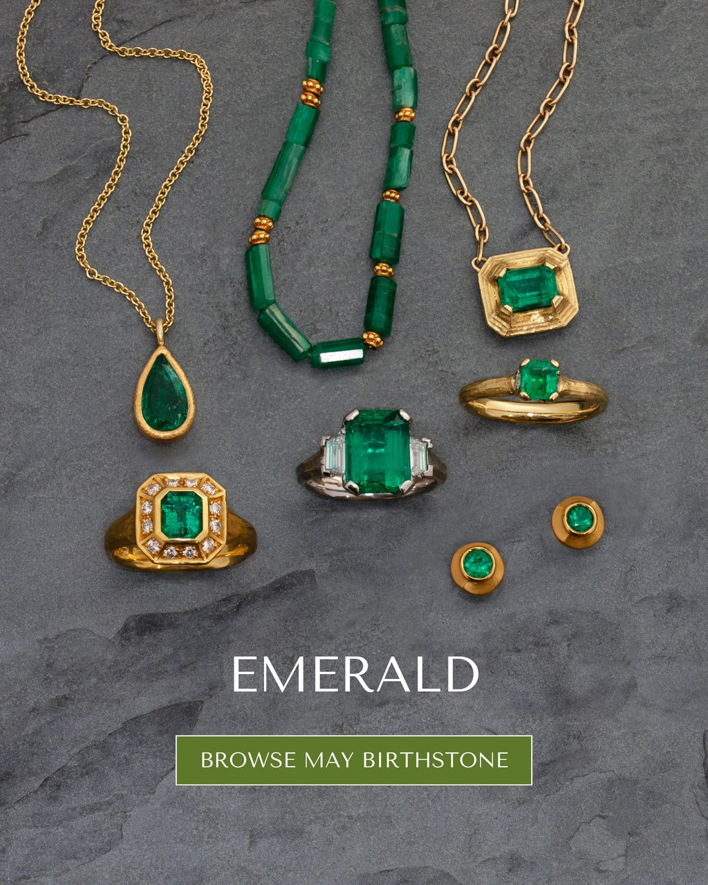 Image: Mixed emerald jewelry on a dark grey slate. Text: EMERALD [BROWSE MAY BIRTHSTONE] button.