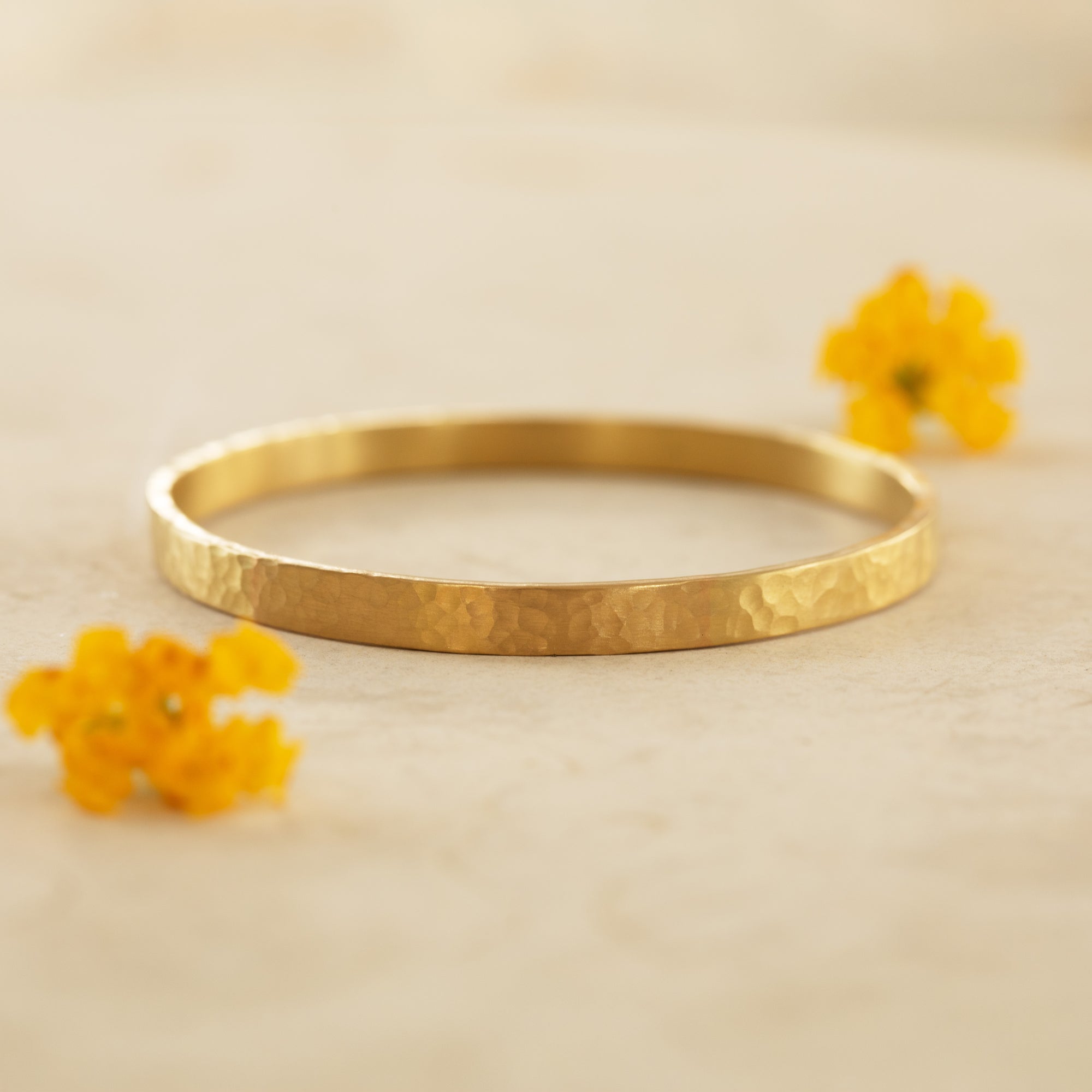 Gold hammer finished bracelet on a tan background