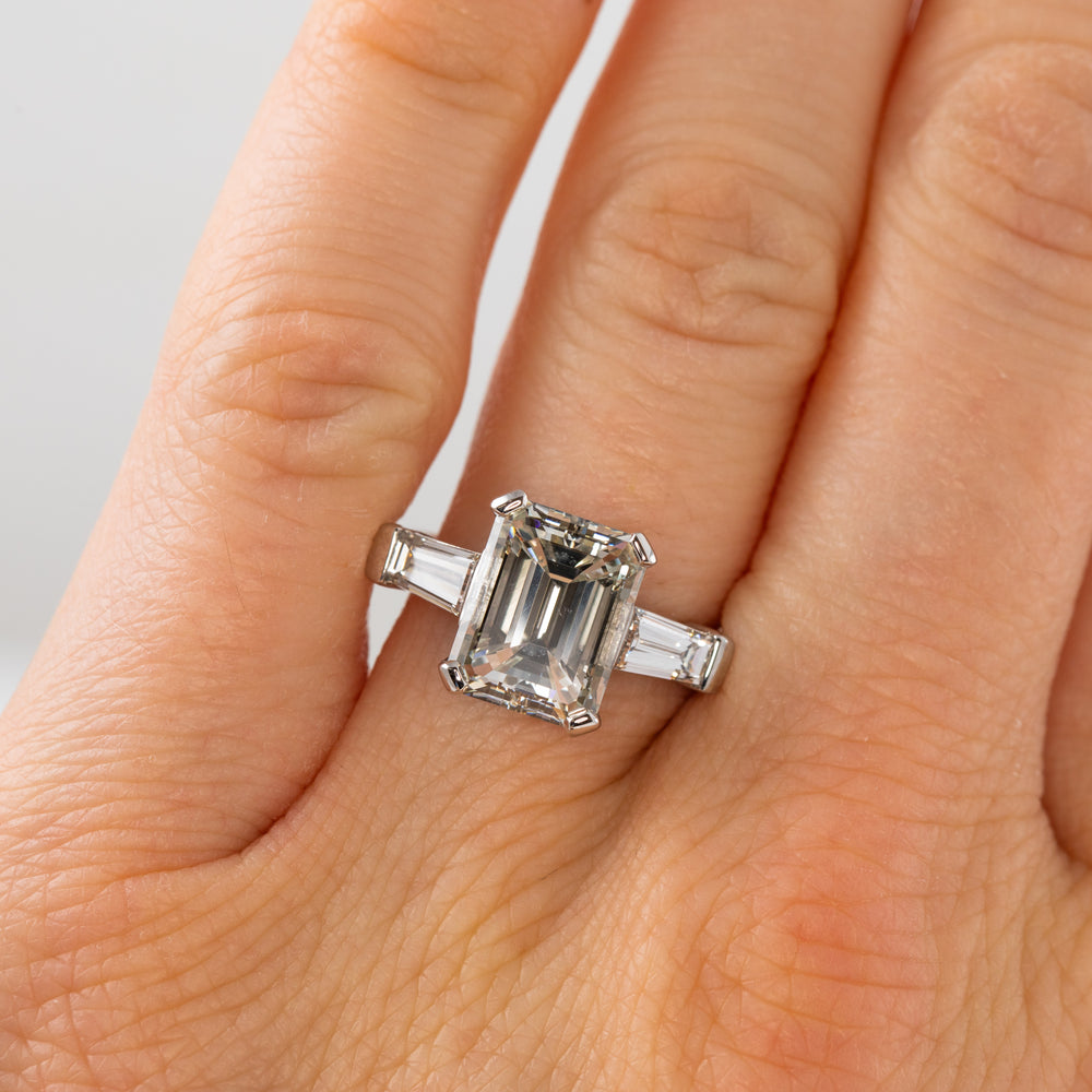 Diamond ring on a person's finger with a plain background