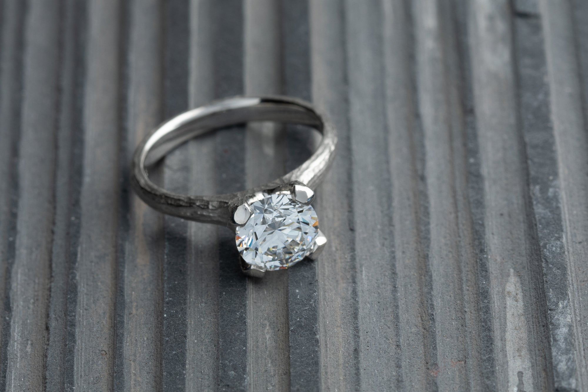 Silver ring with a diamond on a textured slate surface