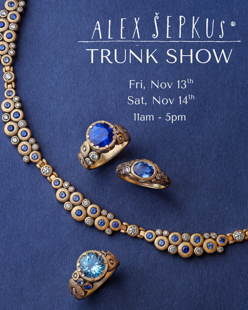 Five colorful rings with varied designs, large vibrant pendants on textured bands. Each ring is placed on blue fabric and photographed on the same blue material. Right hand side text reads: ALEX SEPKUS, NEW YORK. TRUNK SHOW, NOVEMBER 13 & 14 11 AM - 5 PM