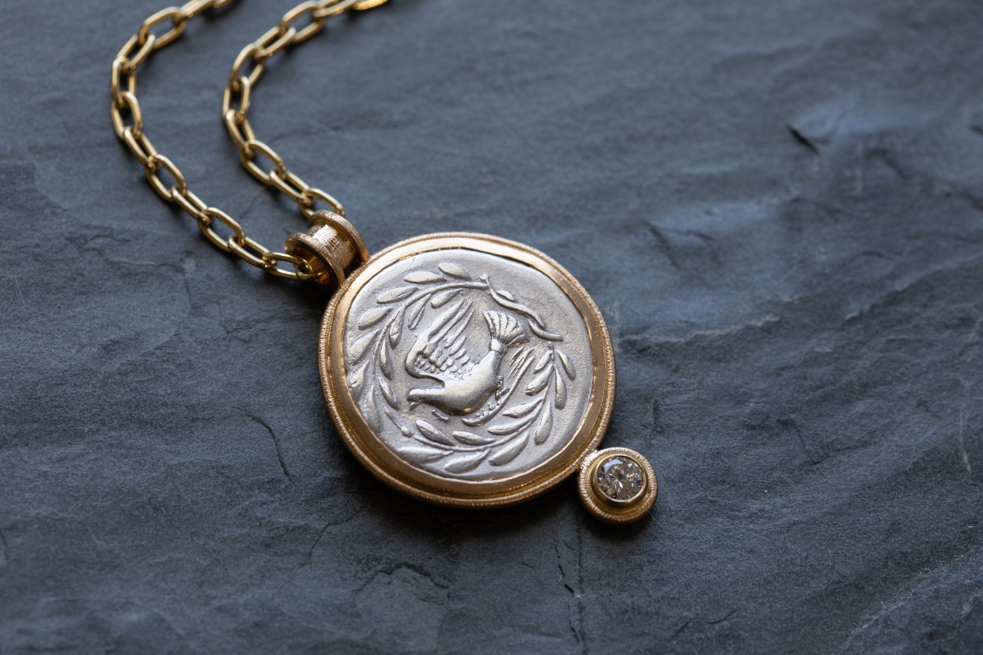 Gold necklace with ancient coin on a dark stone surface