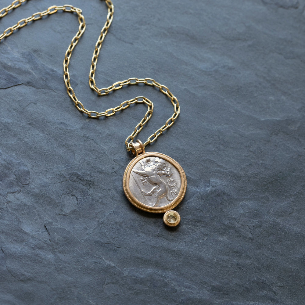 Gold necklace with ancient coin on a dark stone surface