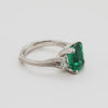 Emerald ring with side diamonds rotating 360 degrees on a white background